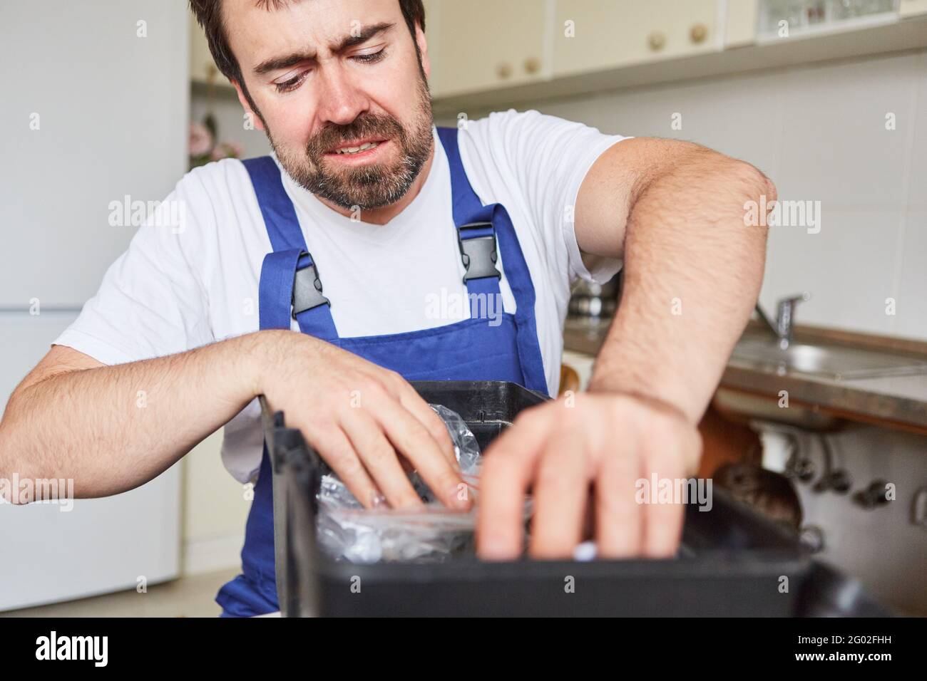 Gestresster Handwerker aus dem Notdienst mit Werkzeugkasten bei Reparaturen In der Küche Stockfoto