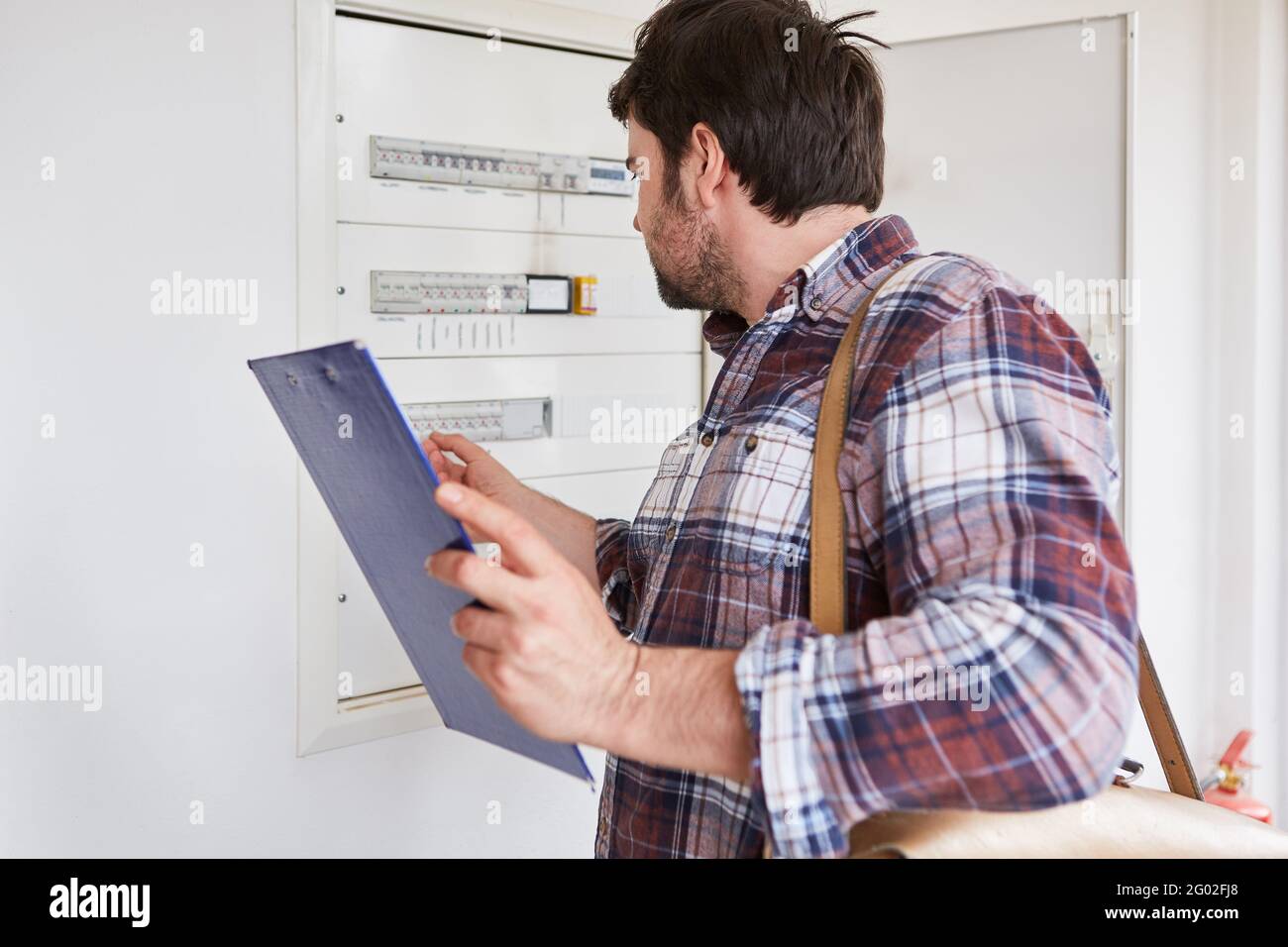 Ein Elektriker mit einer Checkliste überprüft die Sicherheit des Verteilerkasten in einer Wohnung Stockfoto