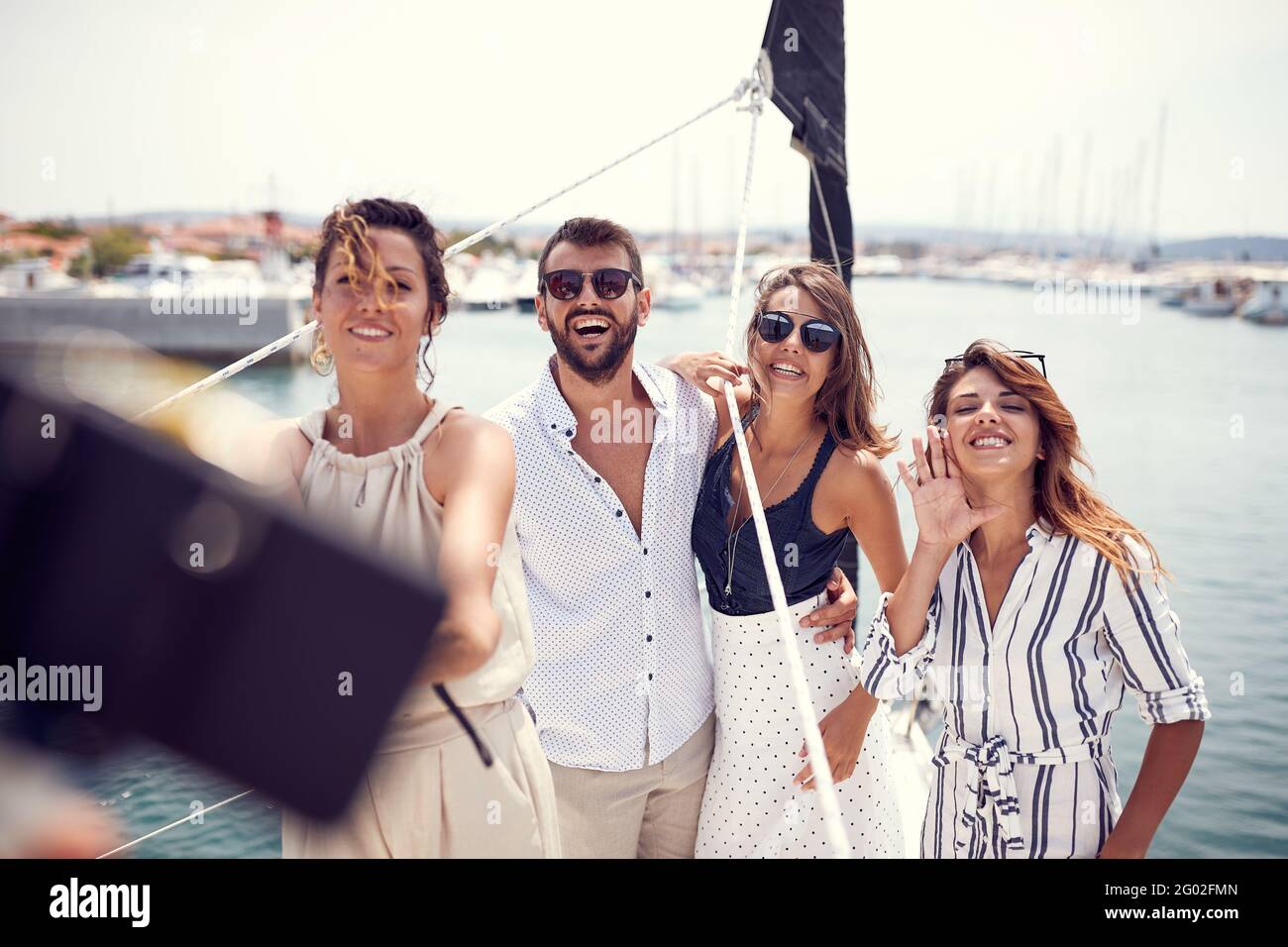 Eine Gruppe junger, hübscher Models posiert für einen Foto auf dem Deck der Yacht während der Durchfahrt Das Dock an einem schönen Sommertag am Meer Stockfoto