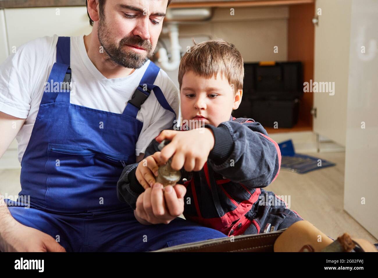 Vater und Sohn als Heimwerker-Team in der Küche Halten Sie ein defektes Absperrventil fest Stockfoto