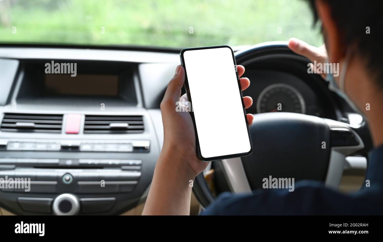 Rückansicht junger Mann mit Mobiltelefon während der Fahrt mit dem Auto. Stockfoto