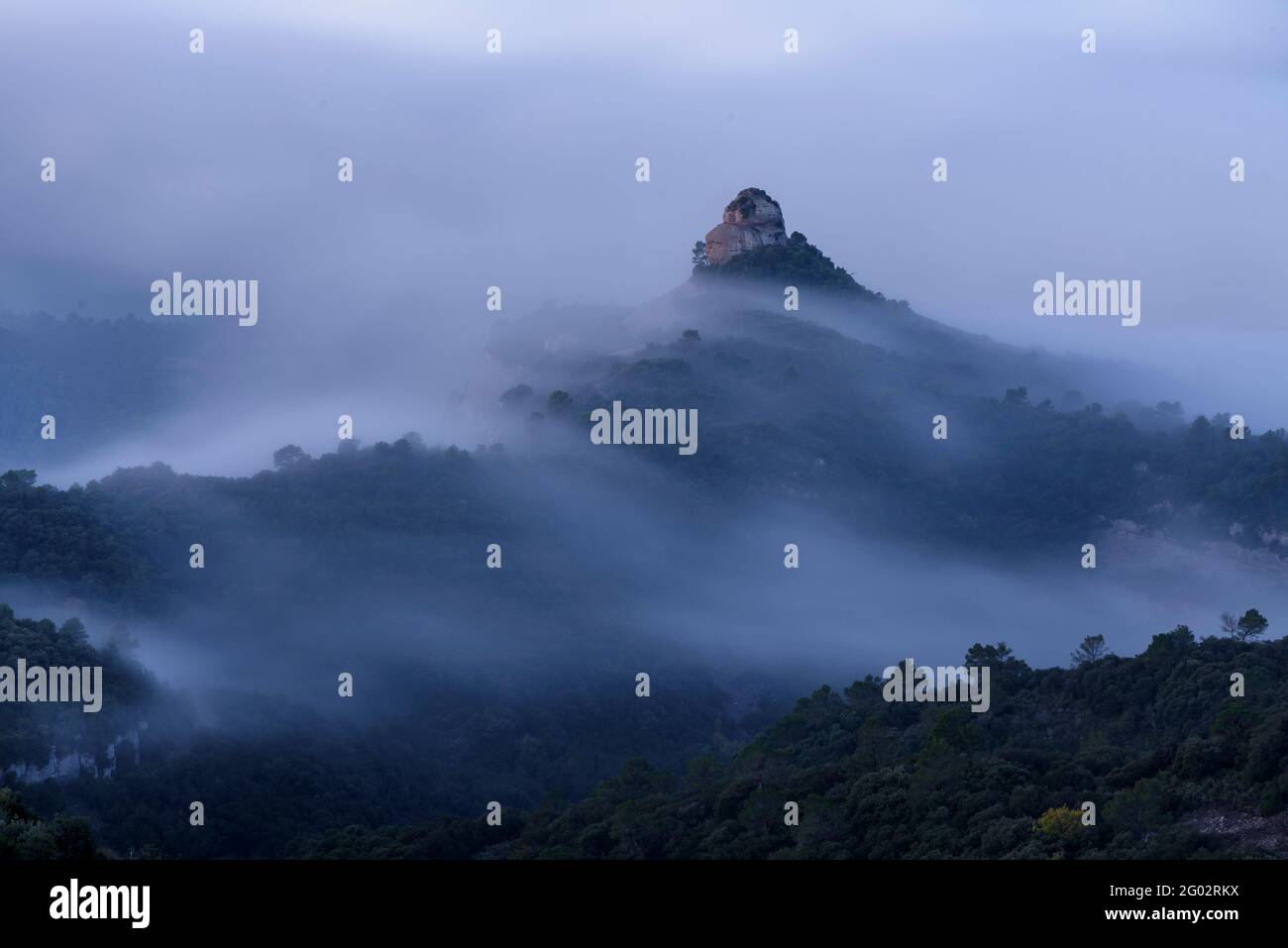 Der Felsen von Paller de tot l'Any bei Sonnenaufgang, umgeben von Nebel (Naturpark Sant Llorenç del Munt i l'Obac, Barcelona, Katalonien, Spanien) Stockfoto