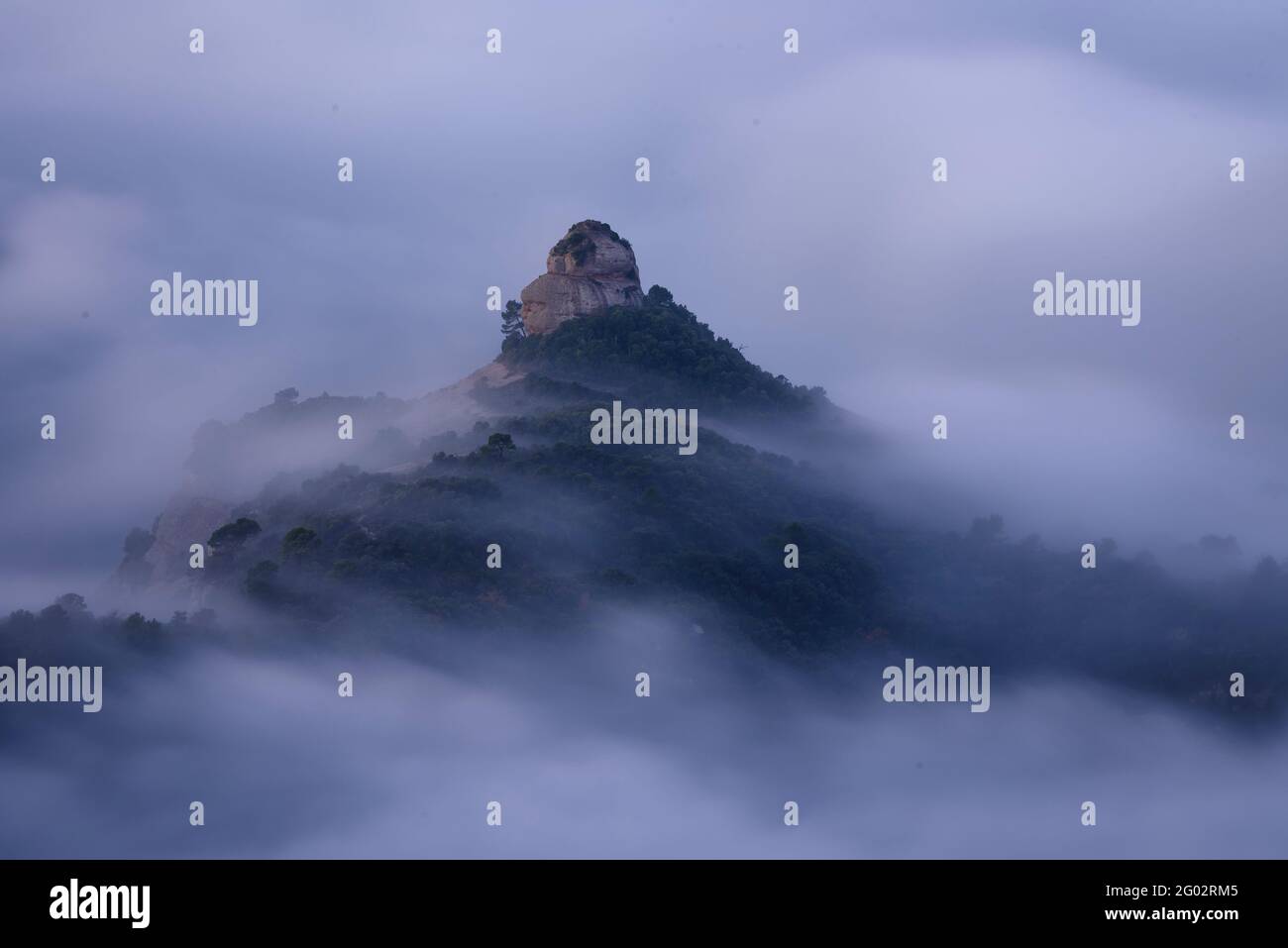 Der Felsen von Paller de tot l'Any bei Sonnenaufgang, umgeben von Nebel (Naturpark Sant Llorenç del Munt i l'Obac, Barcelona, Katalonien, Spanien) Stockfoto