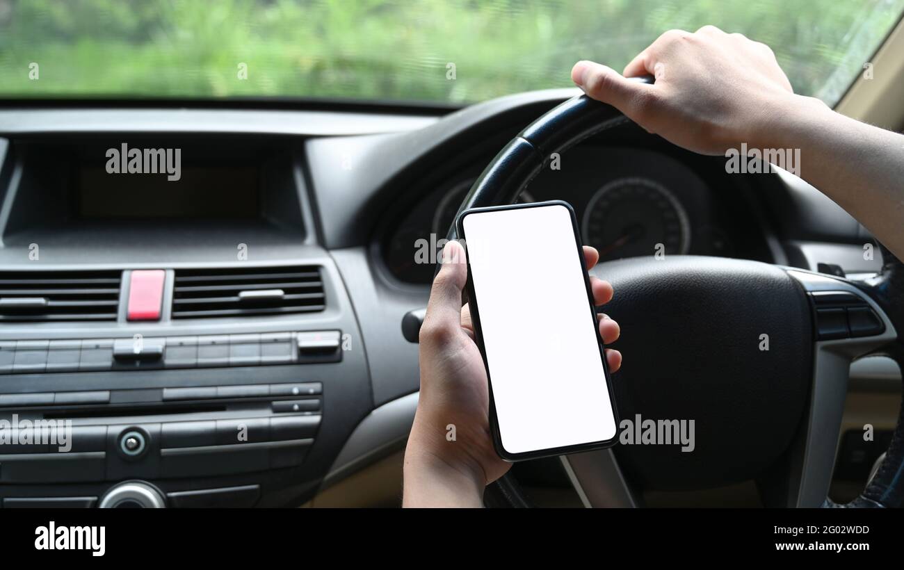 Nahaufnahme eines jungen Mannes, der während des Autofahrens Smartphone benutzt. Stockfoto