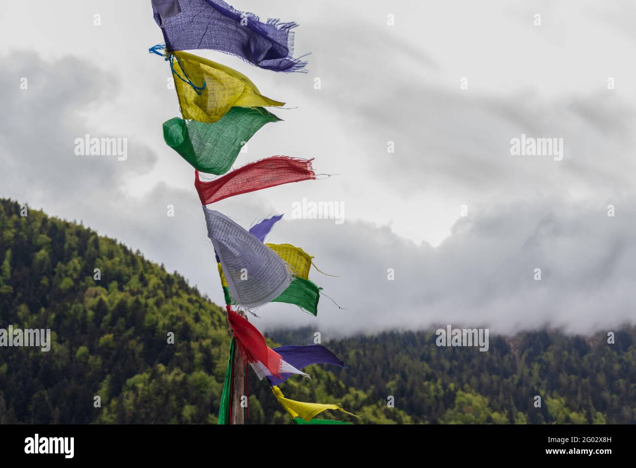 Farbige tibetische Fahnen winken. Berge, Wolken und Himmel im Hintergrund. Konzept der tibetischen Kultur, Buddhismus. Stockfoto