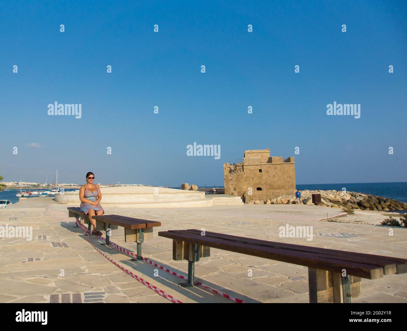 PAPHOS, ZYPERN - 13. Aug 2012: Frau sitzt auf einer Bank am Hafen Stockfoto