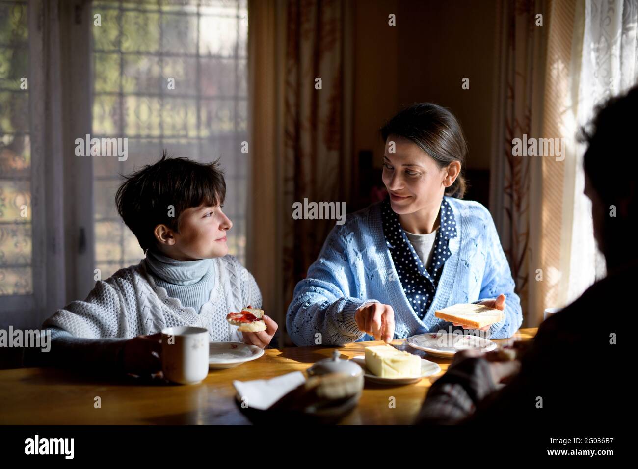 Porträt eines glücklichen armen kleinen Mädchens mit Eltern, die zuhause essen, Armutskonzept. Stockfoto