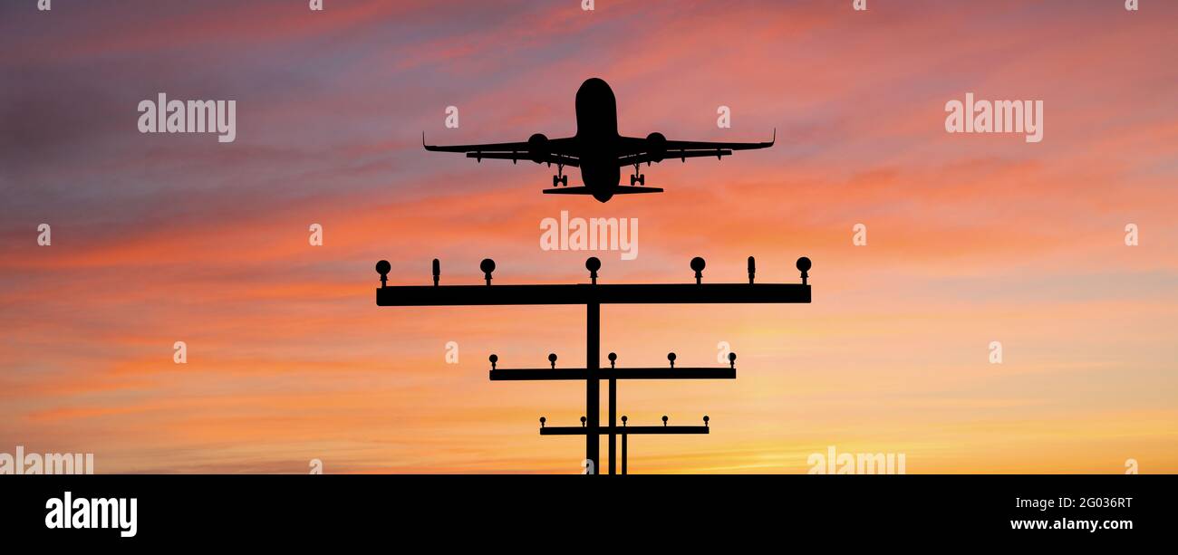 Silhouette eines Flugzeuges, das am Flughafen gegen den landet Hintergrund des Sonnenuntergangs Stockfoto