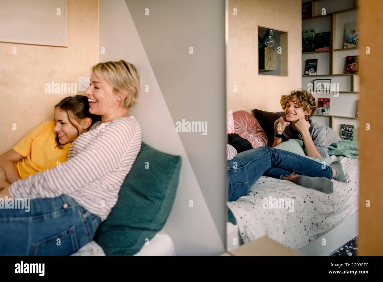 Lächelnder Junge, der auf dem Bett liegt, während er Mutter und Schwester durch den Spiegel betrachtet Stockfoto