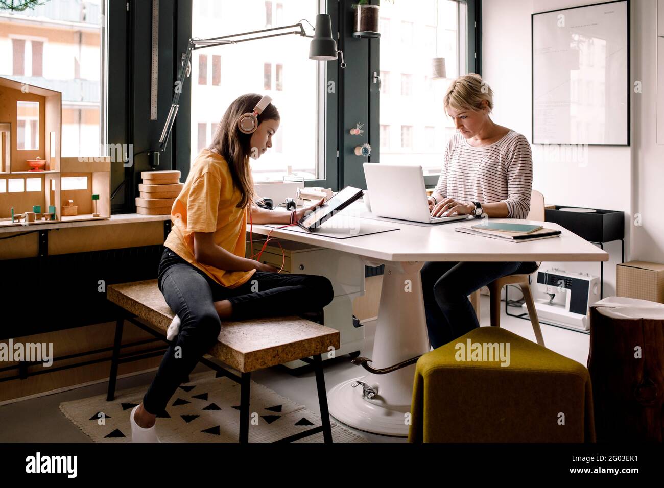 Geschäftsfrau, die zu Hause arbeitet, während ihre Tochter mit einem digitalen Tablet lernt Stockfoto