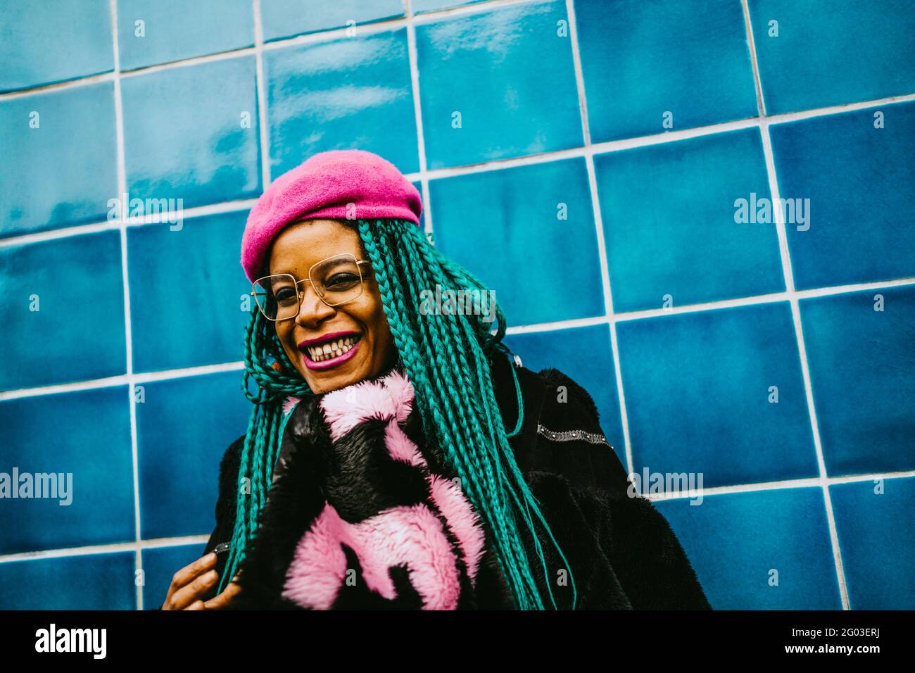Porträt einer fröhlichen Frau mittleren Erwachsenen, die an der blau gefliesten Wand steht Stockfoto