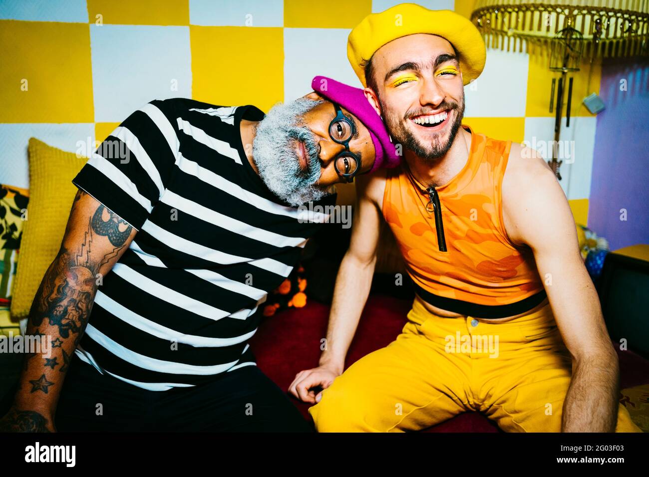 Porträt eines älteren Mannes mit Kopf auf der Schulter eines jungen männlichen Freundes im Wohnzimmer Stockfoto