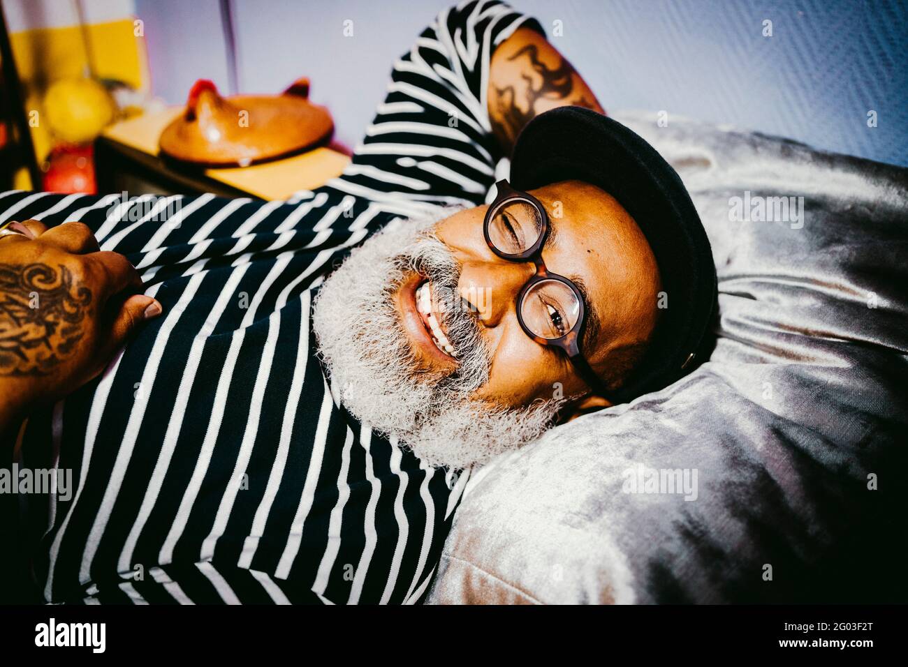 Porträt eines lächelnden älteren Mannes, der zwinkert, während er zu Hause liegt Stockfoto