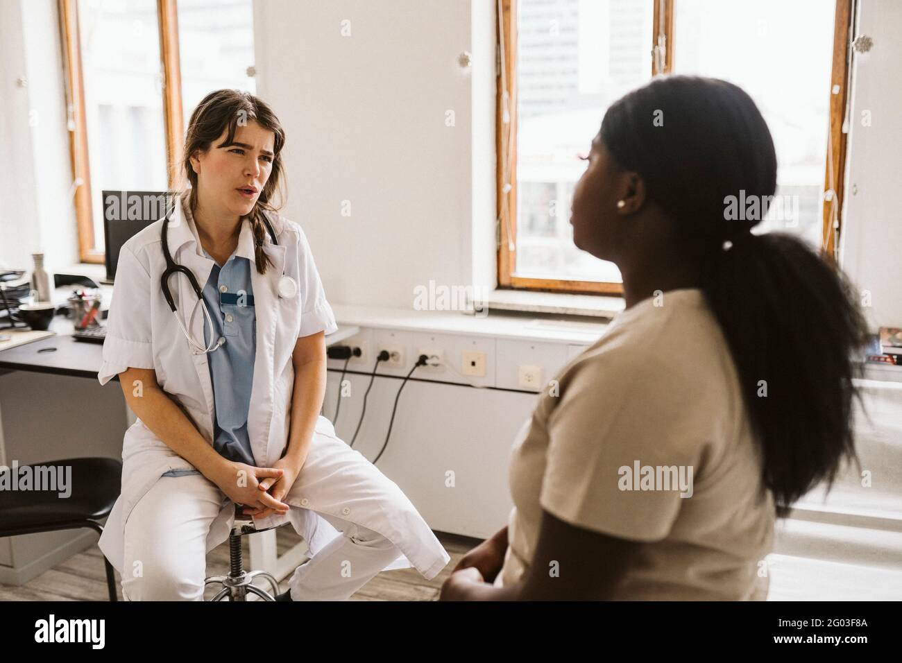 Ärztin, die mit dem Patienten während der Konsultation in der medizinischen Klinik Stockfoto