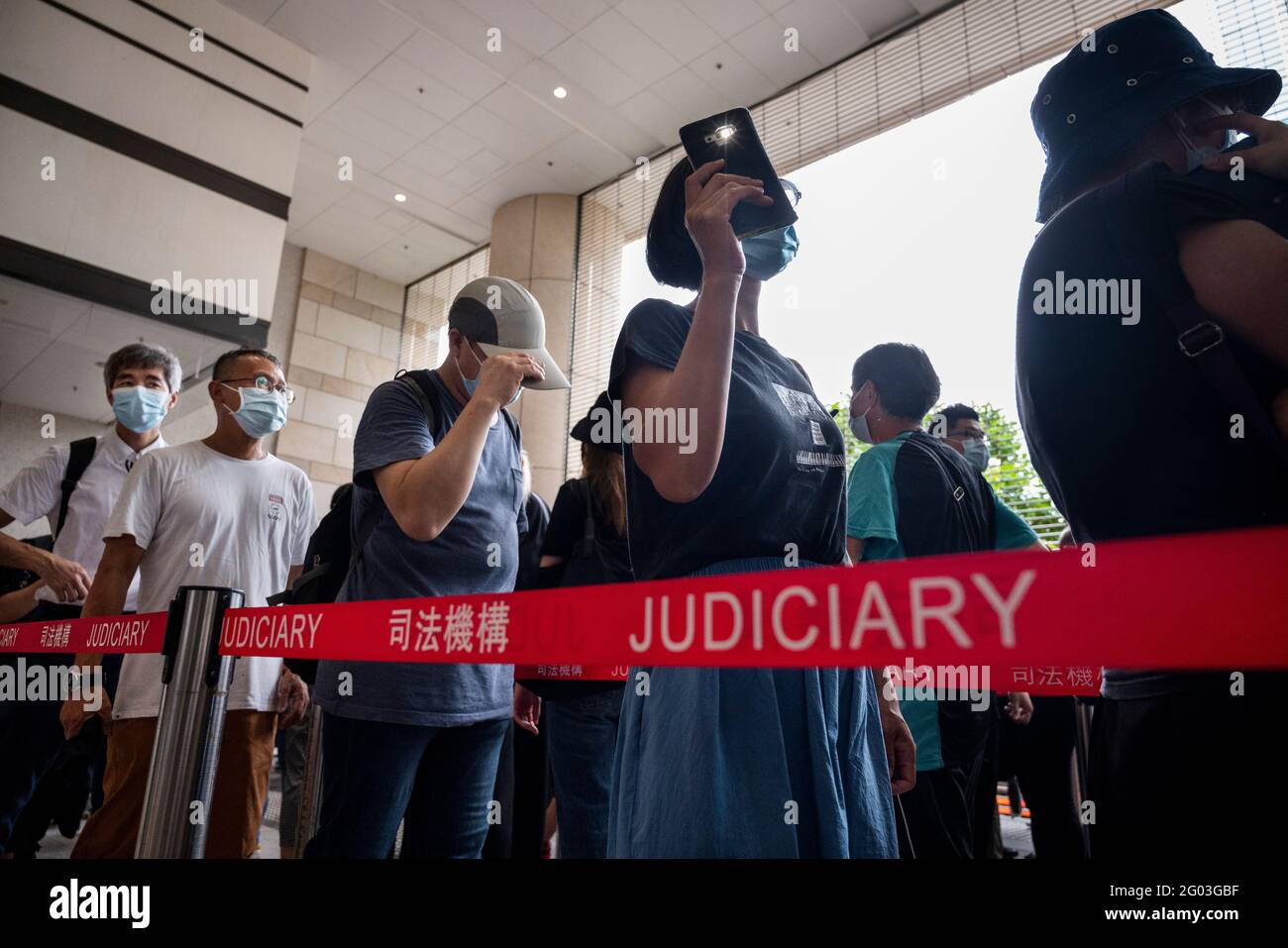 Hongkong, China. Mai 2021. Eine Unterstützerin zündet ihr Handy an, während sie sich am West Kowloon Law Courts Building in Hongkong ansteht.47 pro-demokratische Aktivisten wurden nach dem nationalen Sicherheitsgesetz angeklagt, weil sie 2020 an einer inoffiziellen Primary teilgenommen hatten, um pro-demokratische Kandidaten für die seit dem Aufschub aufgeschobene Legislative zu wählen Wahl. Kredit: SOPA Images Limited/Alamy Live Nachrichten Stockfoto