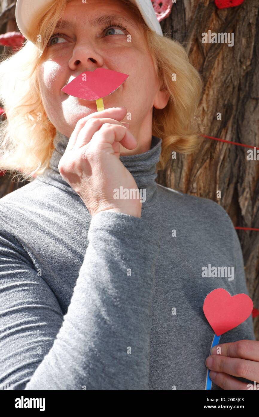 Eine Frau mit Herzkranzen hält Papierlippen und ein Herz als Symbol der Liebe. Welt-Kuss-Tag. Stockfoto