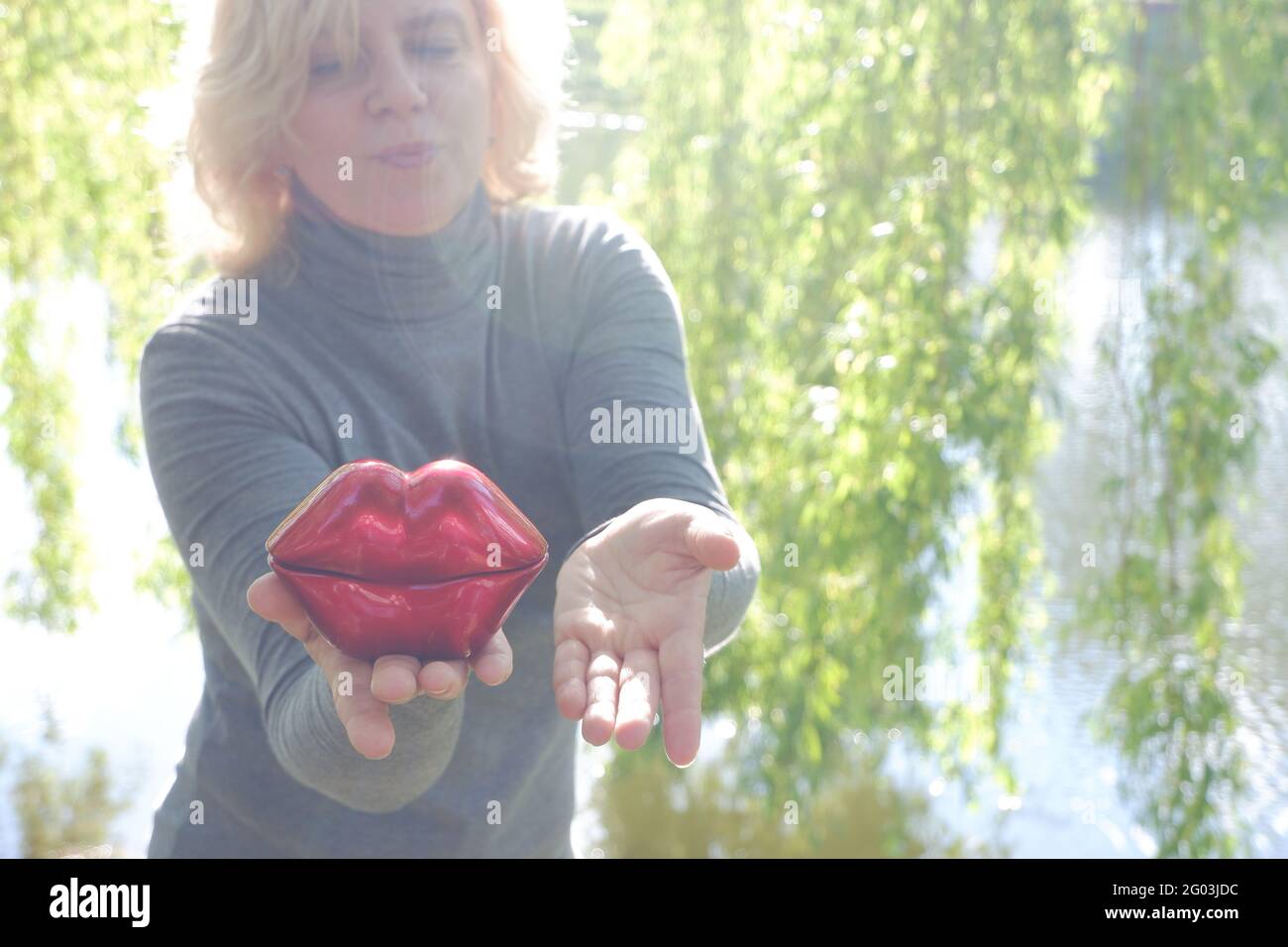 Das Mädchen küsst sich mit ihren großen roten dekorativen Lippen. Welt-Kuss-Tag. Stockfoto