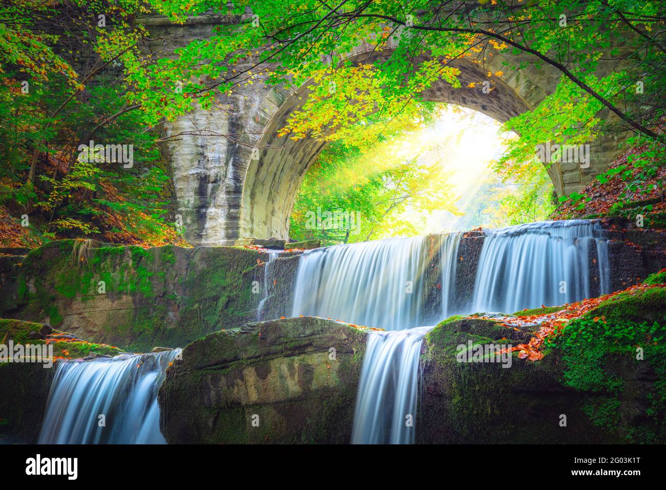 Freshi Landschaft - Fluss Wasserfall in bunten Bergwaldpark Mit alter Brücke und Sonne Stockfoto