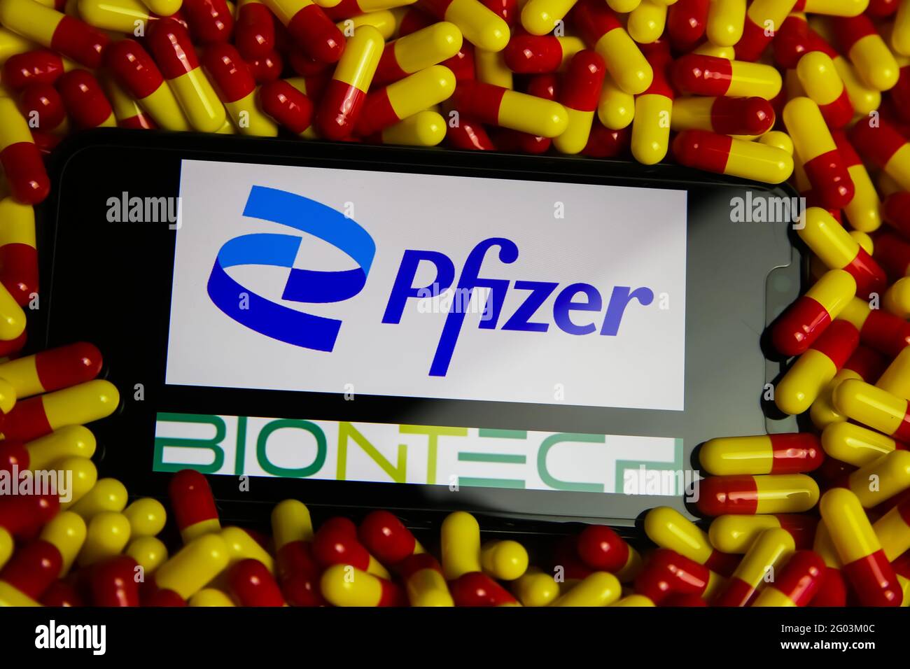 Viersen, Deutschland - Mai 9. 2021: Nahaufnahme des Handybildschirms mit Logo-Schriftzug von Pfizer und BioNTech Pharmaunternehmen im Pillenstapel (FOC Stockfoto