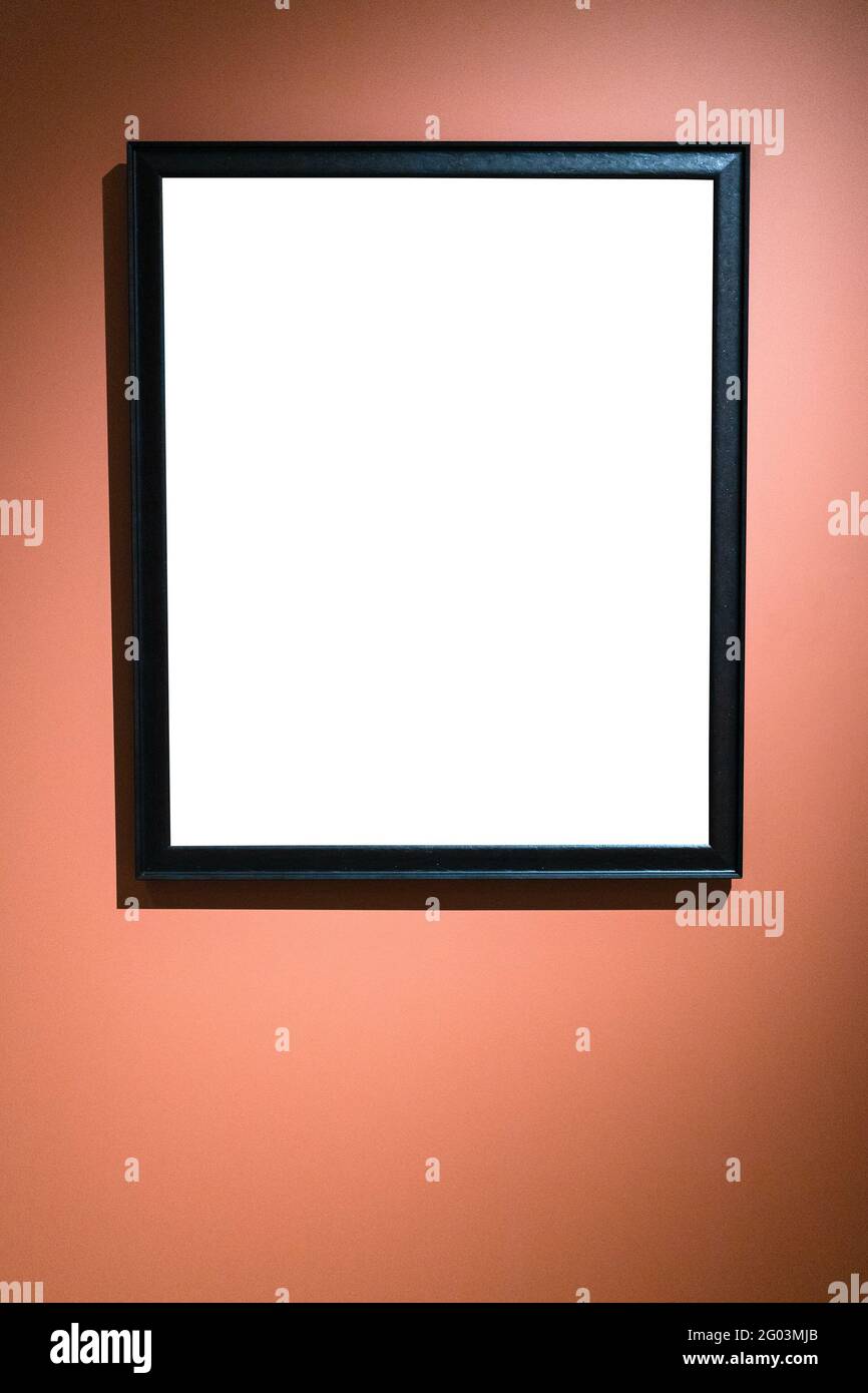 Vertikaler enger schwarzer Bilderrahmen mit ausgeschnitzenem Canvas auf Rot Braune Wand Stockfoto