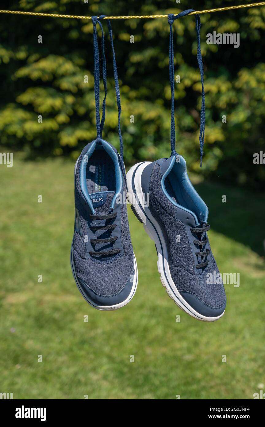 Ein Paar Sketchers-Trainer, die an einer Wäscheleine hängen Nach dem Waschen in einer Waschmaschine Stockfoto