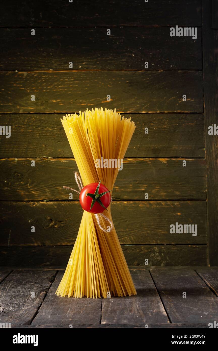 Komposition mit Spaghetti und Kirschtomaten. Tomate in der Mitte der Spaghetti. Stockfoto