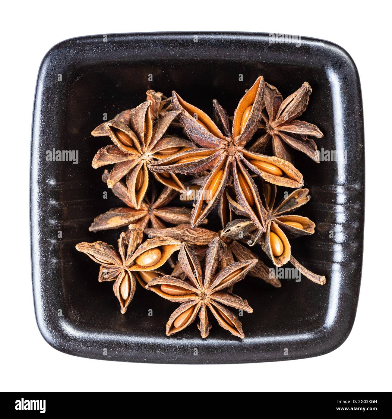 Draufsicht auf getrocknete Sternanisfrüchte (Badian) in Schwarz Schale isoliert auf weißem Hintergrund Stockfoto