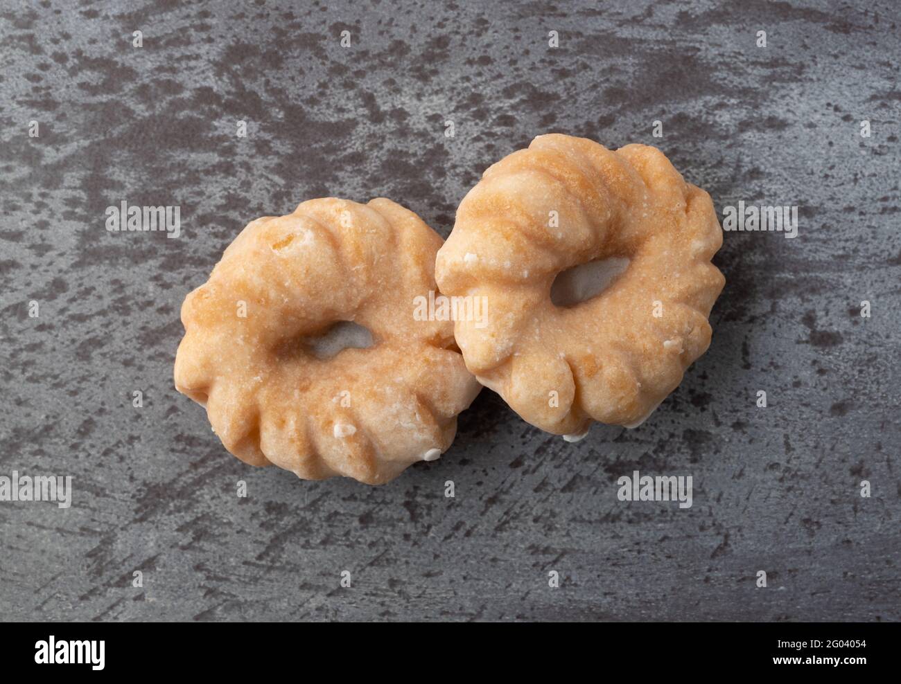 Draufsicht auf zwei krabbelförmige Donuts auf meliertem grauen Hintergrund. Stockfoto