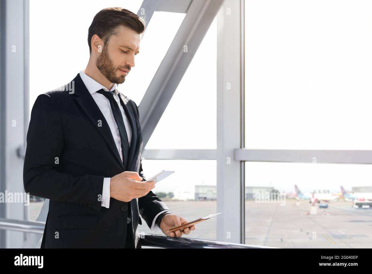 Wohlhabender Geschäftsmann, der per Smartphone auf die Abreise wartet und E-Mails abcheckt Stockfoto