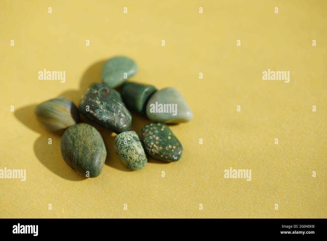Haufen von grünen Kieselsteinen an gelber sonniger Tafel. Stockfoto