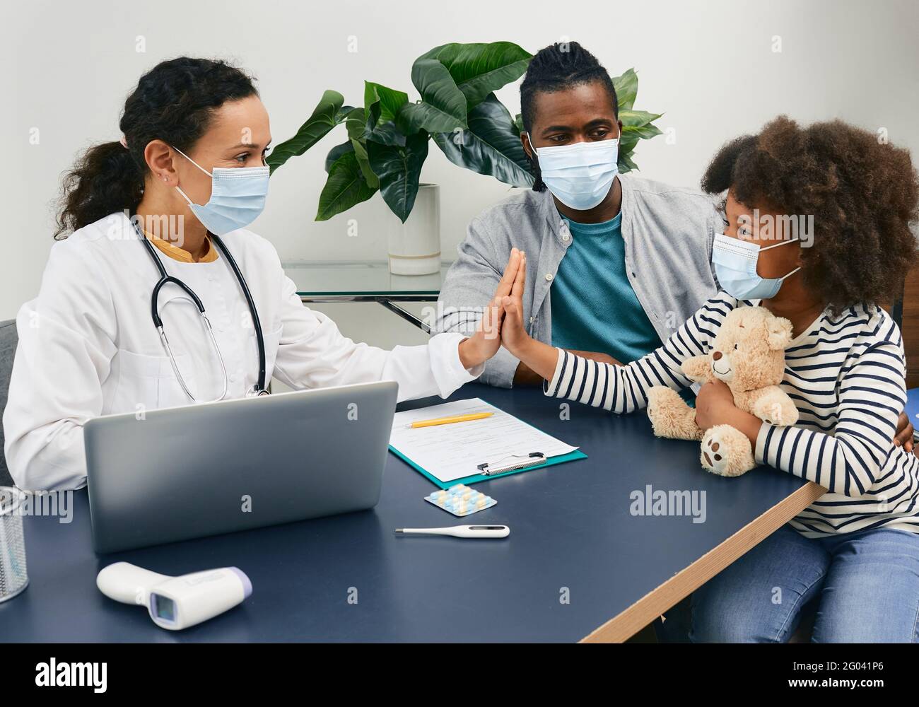 Kinderarztberatung. Afroamerikanisches Mädchen mit ihrem Dafy, der bei der Arztbefragung Schutzmasken trägt Stockfoto