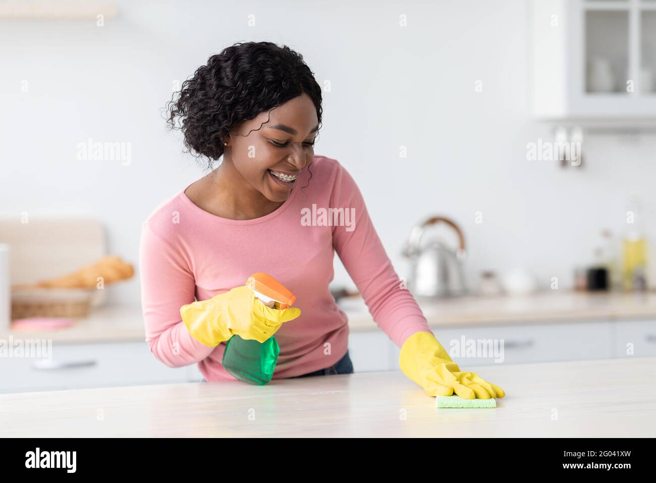 Hübsche afroamerikanische junge Frau in Gummihandschuhen Reinigungstisch Stockfoto