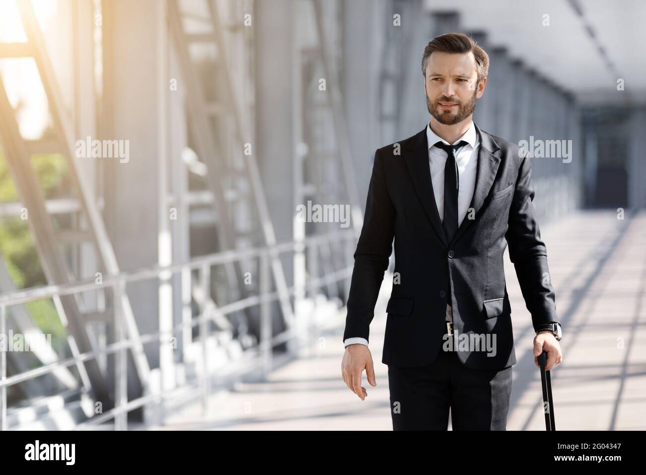 Wohlhabender Geschäftsmann mit Gepäck, der am Flughafen vorbei läuft Stockfoto