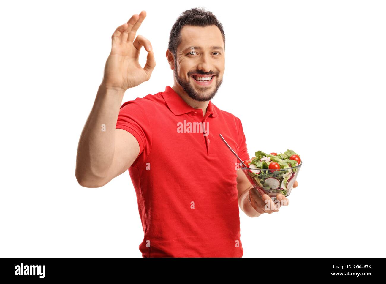 Junger Mann in einem roten T-Shirt mit einem frischen Salat In einer Schüssel und gestikulierenden guten Zeichen isoliert auf weiß Hintergrund Stockfoto