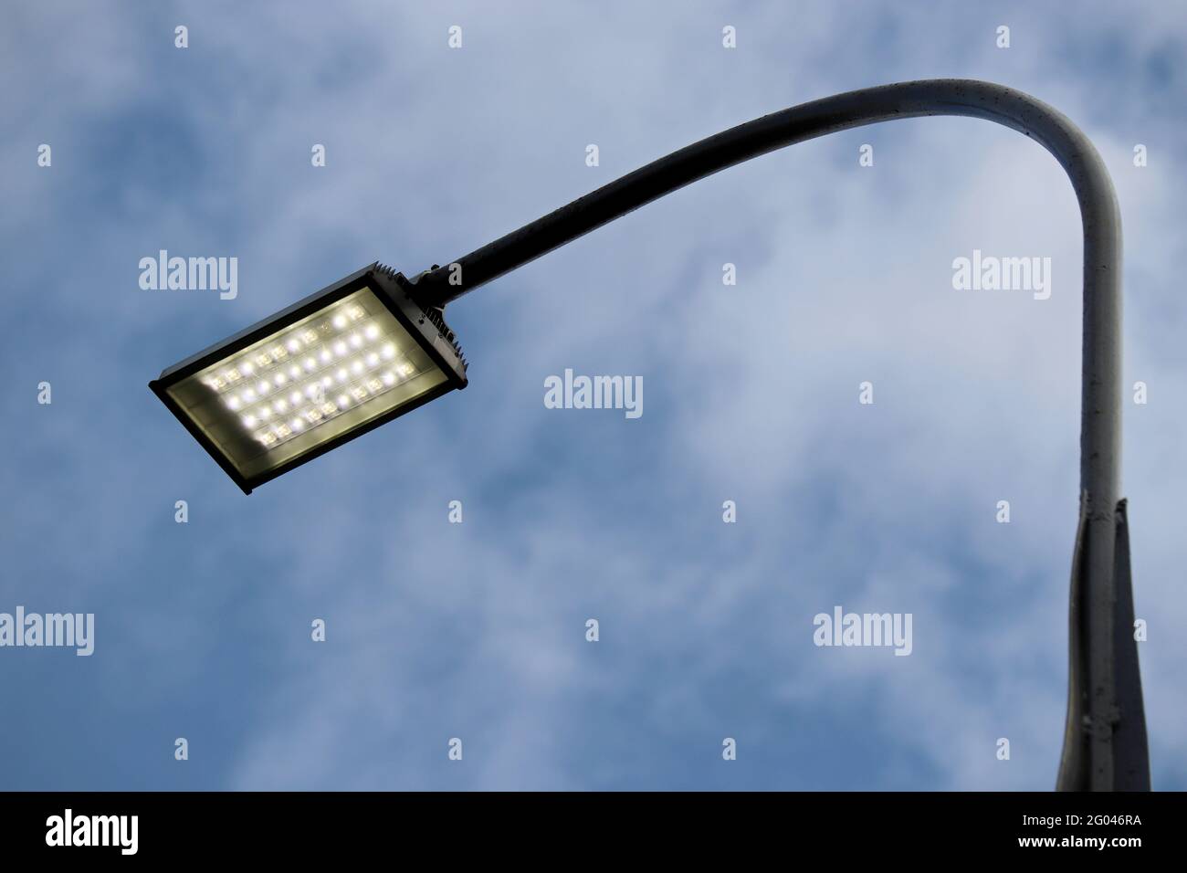 LED-Straßenlampe, die auf dem Hintergrund des blauen Himmels mit Wolken leuchtet. LED-Leuchten sparen elektrische Energie Stockfoto