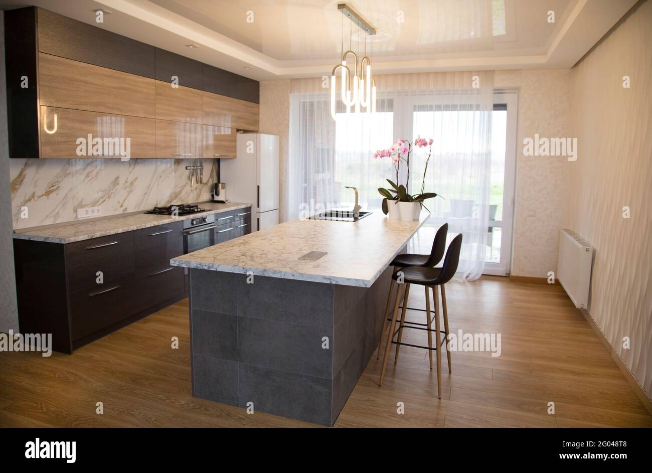 Moderne und sonnige Küche mit einer Marmorkücheninsel in der Mitte. Design, Inneneinrichtung. Stockfoto