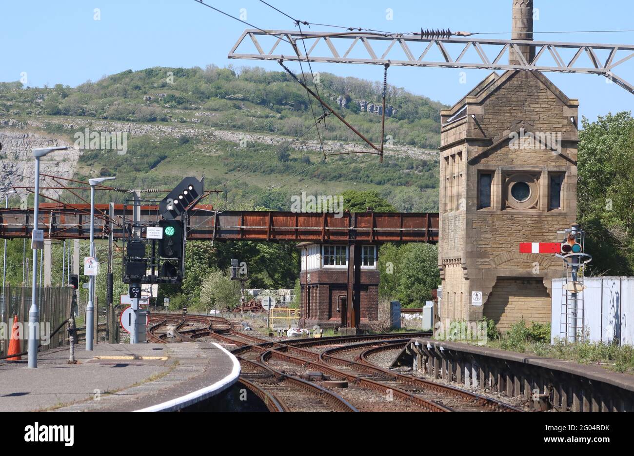 Blick auf ein Federsignal auf der Oberseite eines Farblichts auf Bahnsteig 2 am Bahnhof Carnforth, das zeigt, dass der nächste Zug direkt an der Kreuzung fährt. Stockfoto