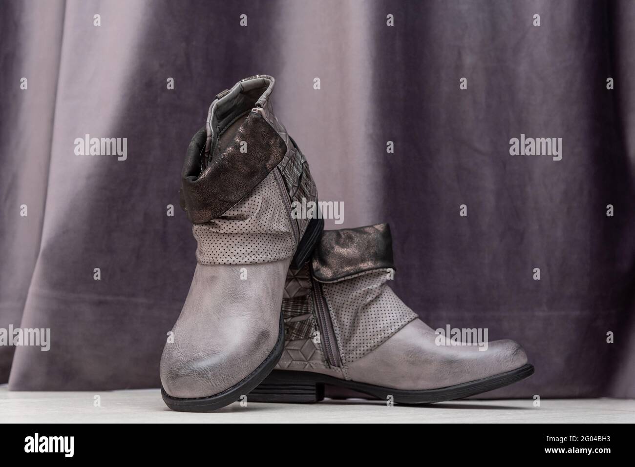 Elegante Damen Stiefeletten auf dem Display in der Nähe lila Vorhang Stockfoto