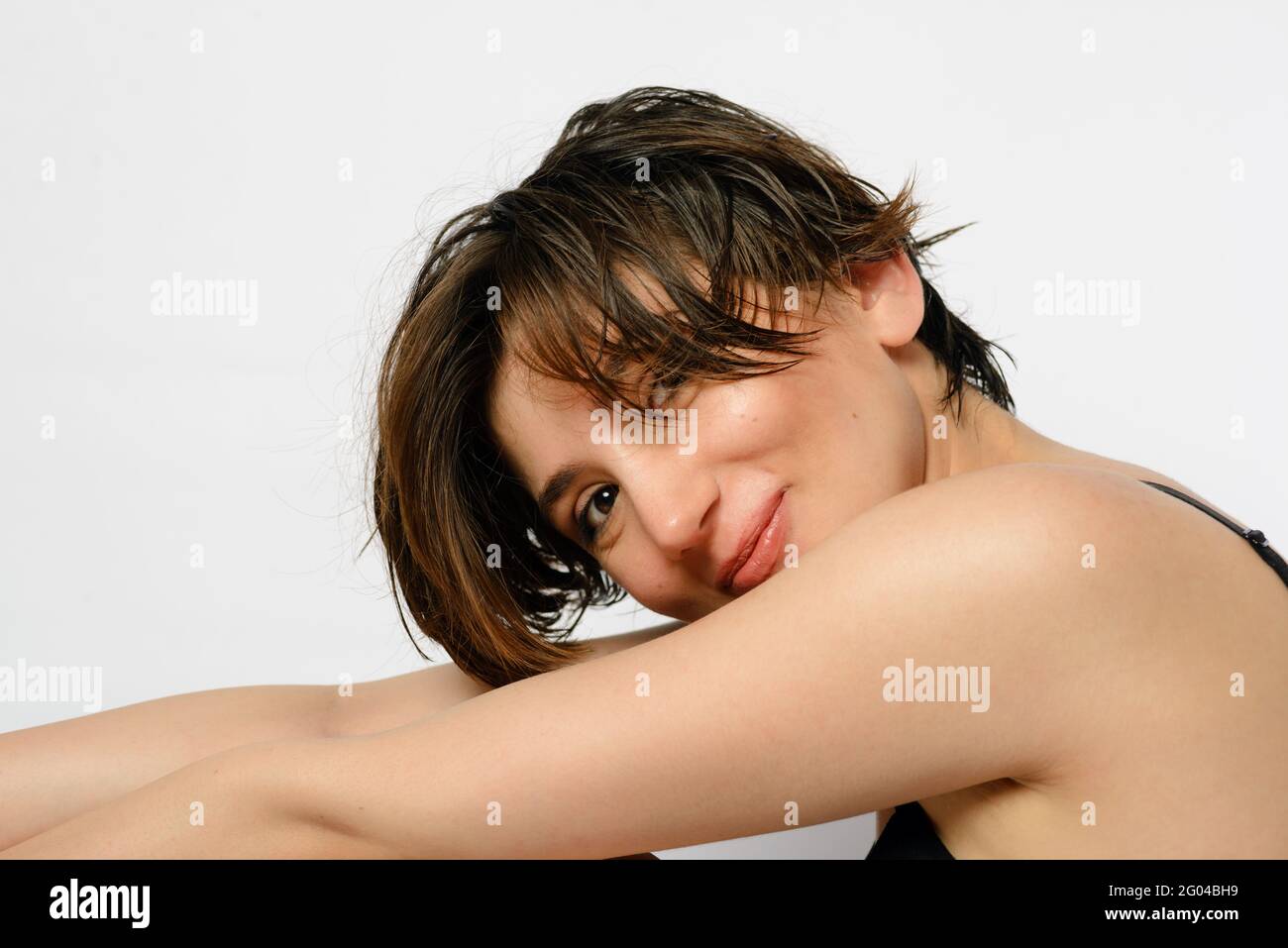 Porträt einer lächelnden jungen Frau mit kurzen und nassen Haaren und einer lustigen Emotion auf ihrem Gesicht auf weißem Hintergrund. Stockfoto