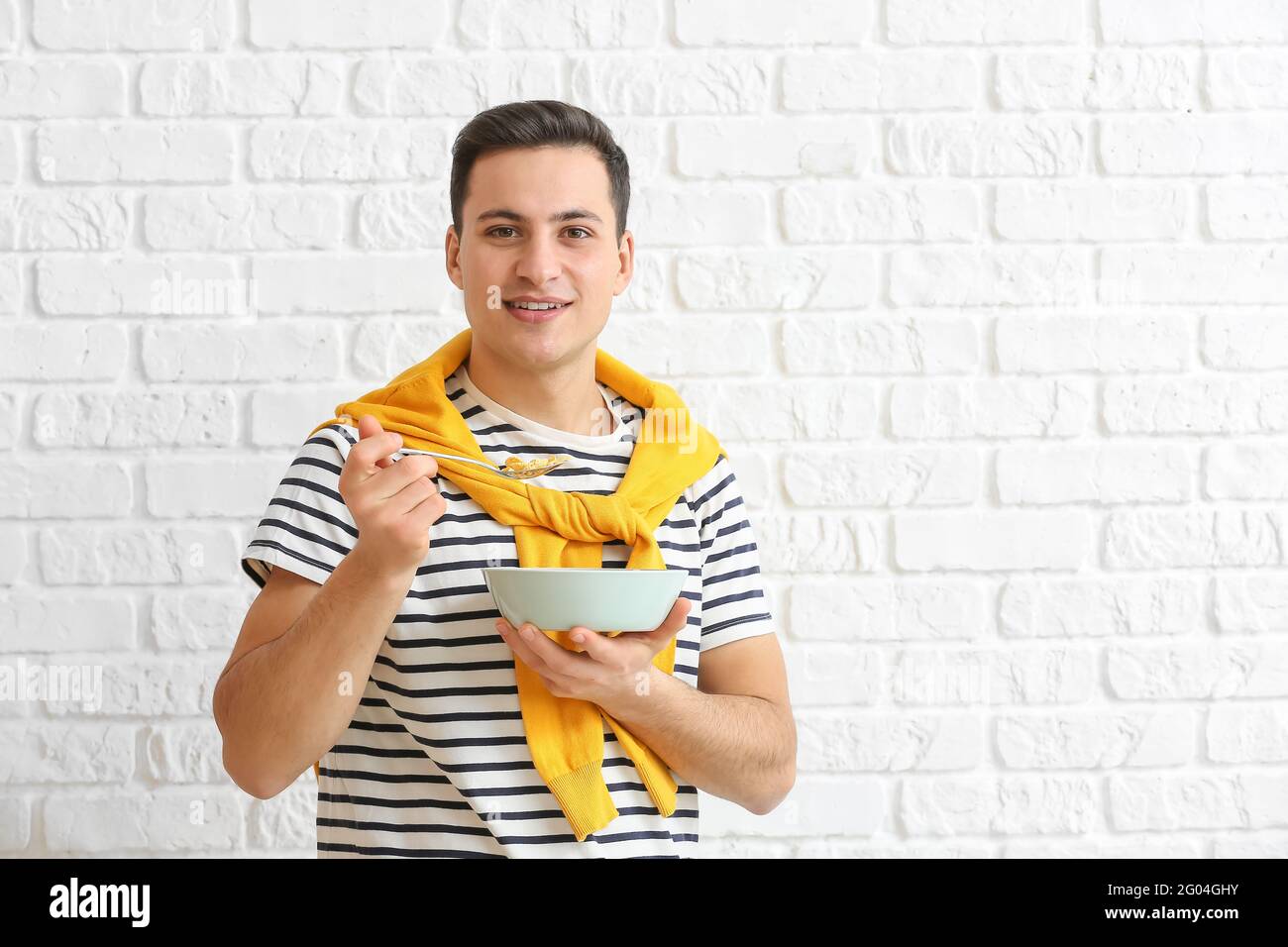 Junger Mann, der auf Backstein Cornflakes isst Stockfoto