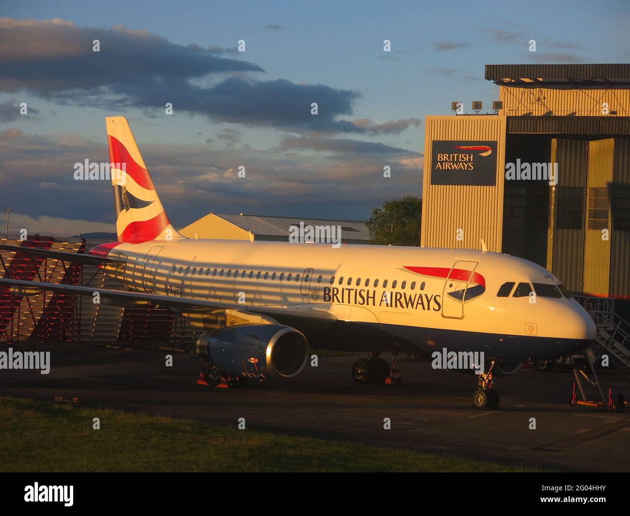 British Airways-Flugzeug vor einem BA-Hangar am Flughafen Glasgow mit dem roten, weißen und blauen Branding. Stockfoto