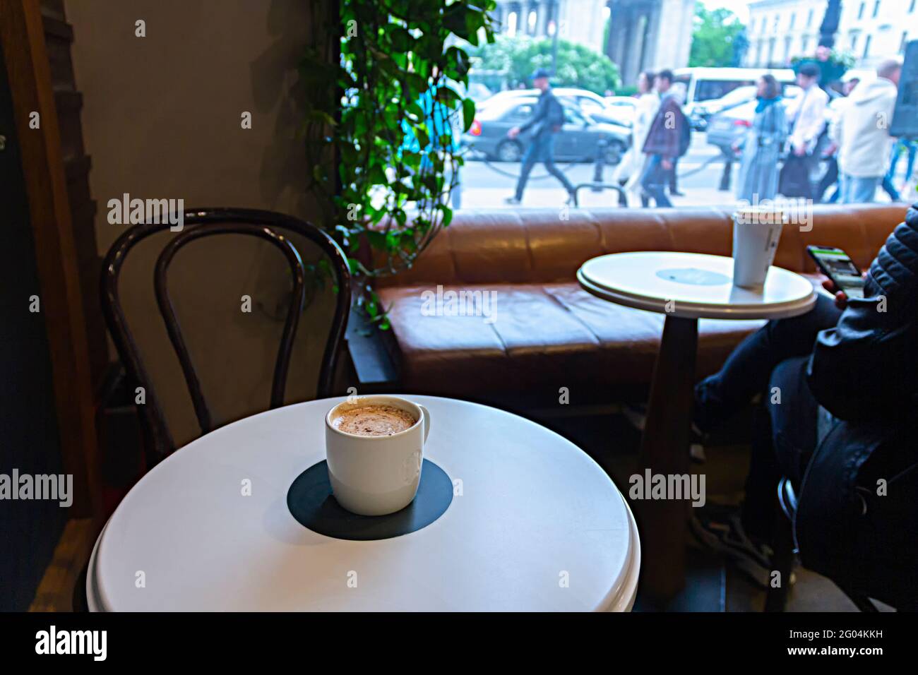 Saint-Petersburg, Russland - 25. Mai 2021: Starbucks Kaffeetasse auf einem Kaffeetisch und laute Straße hinter dem Fenster Stockfoto