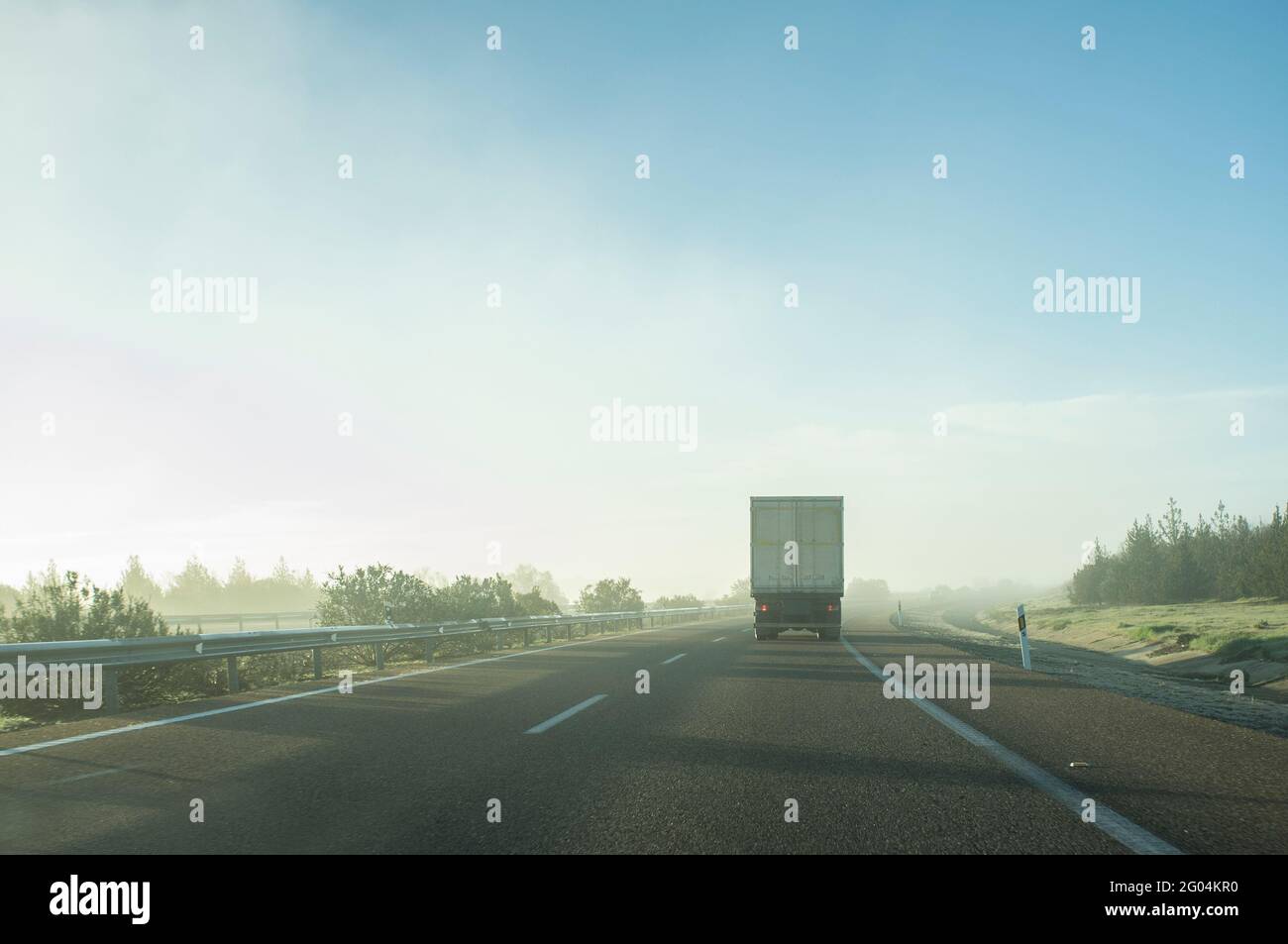 Fahrt hinter einem LKW unter dem Morgennebel. Fahrkonzept bei schlechtem Wetter Stockfoto