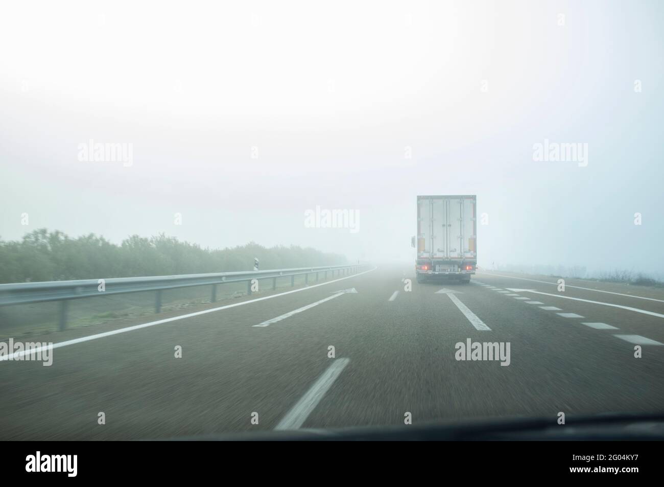 Fahren hinter einem LKW unter dichtem Nebel. Fahrkonzept bei schlechtem Wetter Stockfoto