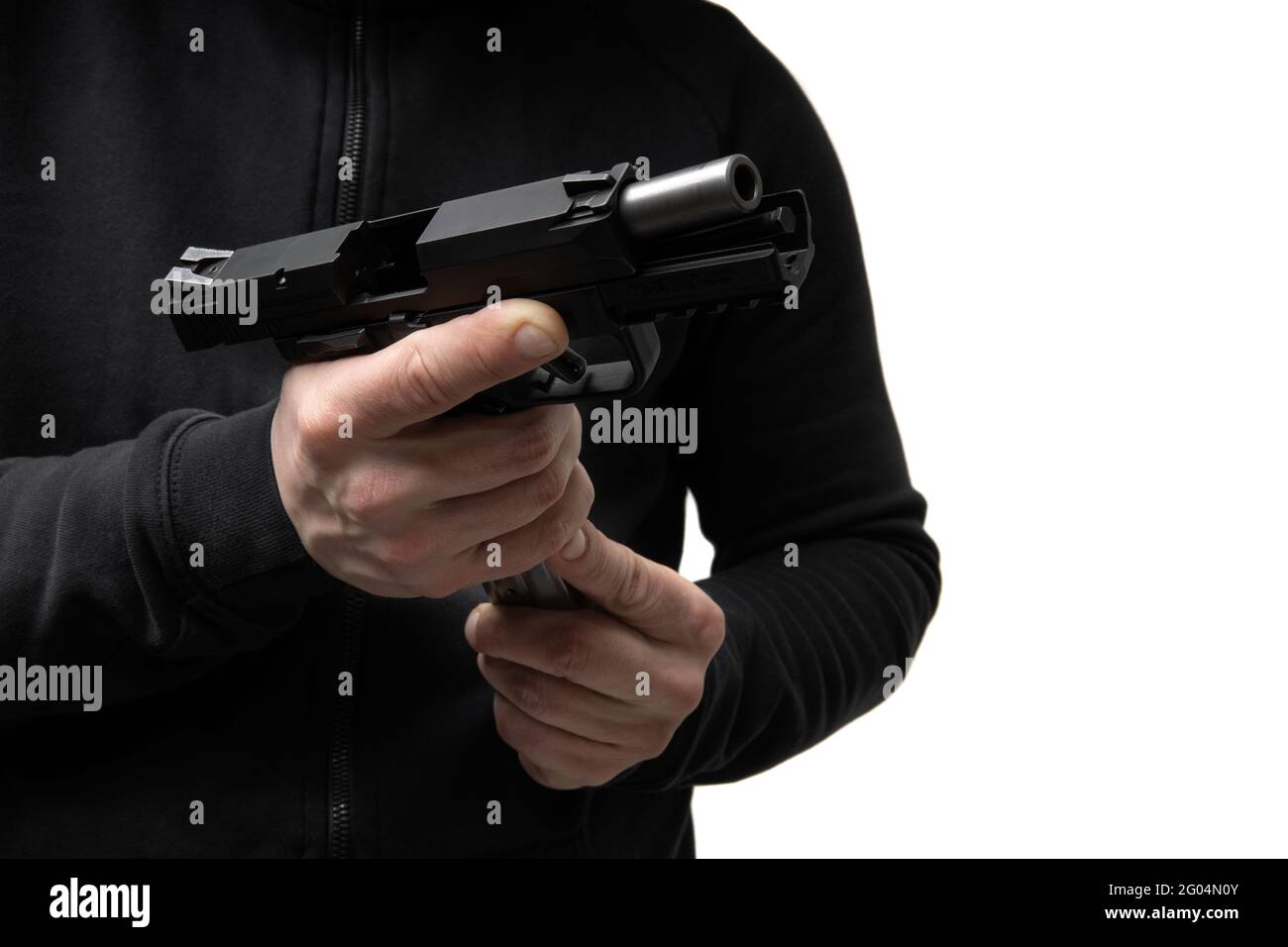 Ein Mann in dunkler Kleidung hält eine Pistole in den Händen und lädt sie  wieder auf. Entladen der Waffe in der Hand Stockfotografie - Alamy