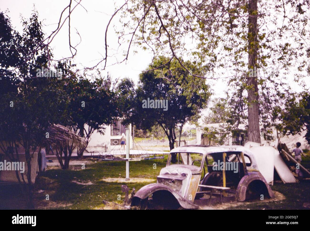 Ein altes verlassene Auto und ein Spielplatz für Kinder An einem Israel Kibutz Stockfoto