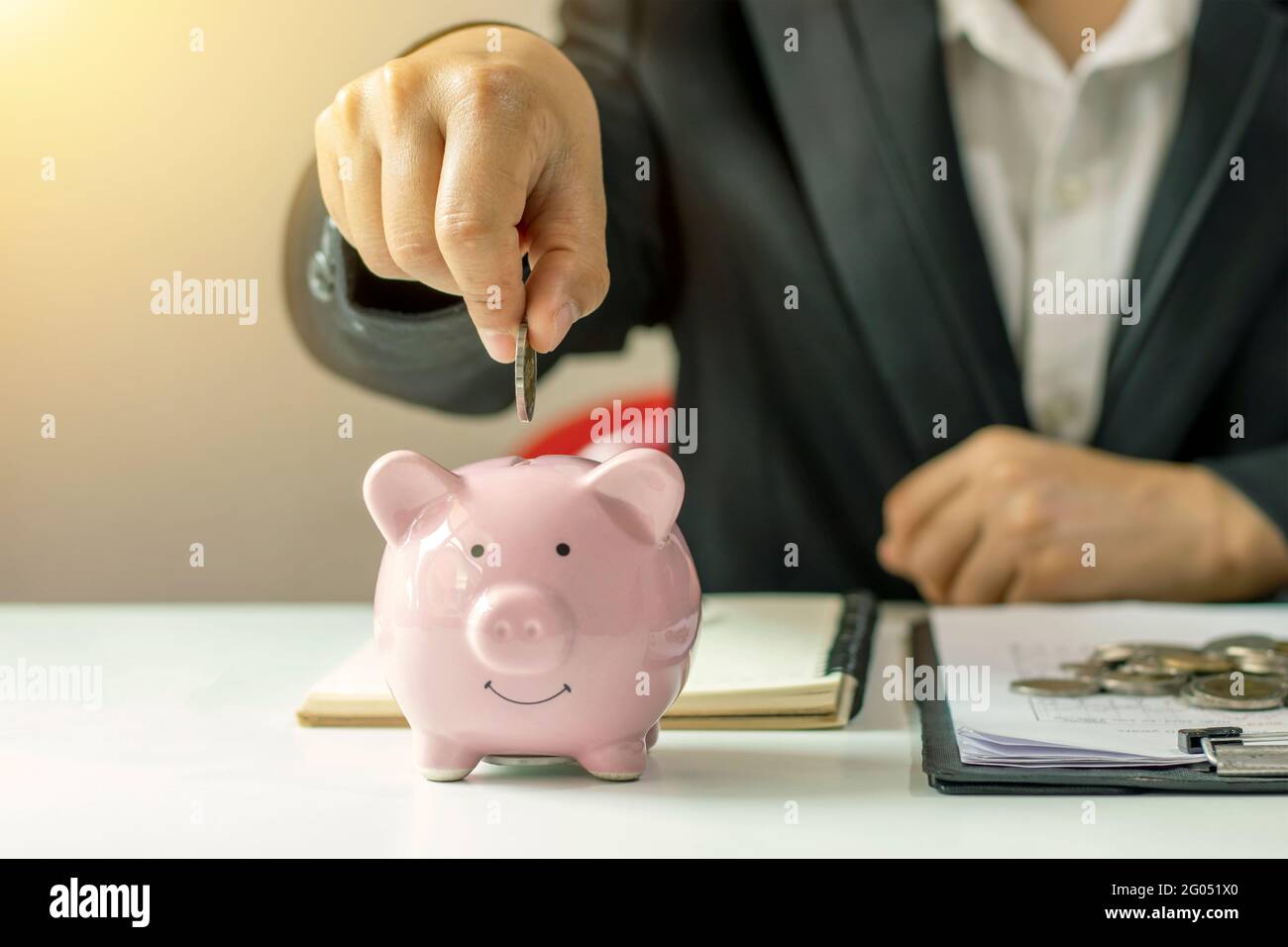 Geschäftsfrauen stecken Geldmünzen in Ferkel, um Geld und finanzielle und Ideen für eine nachhaltige Zukunft zu sparen. Stockfoto