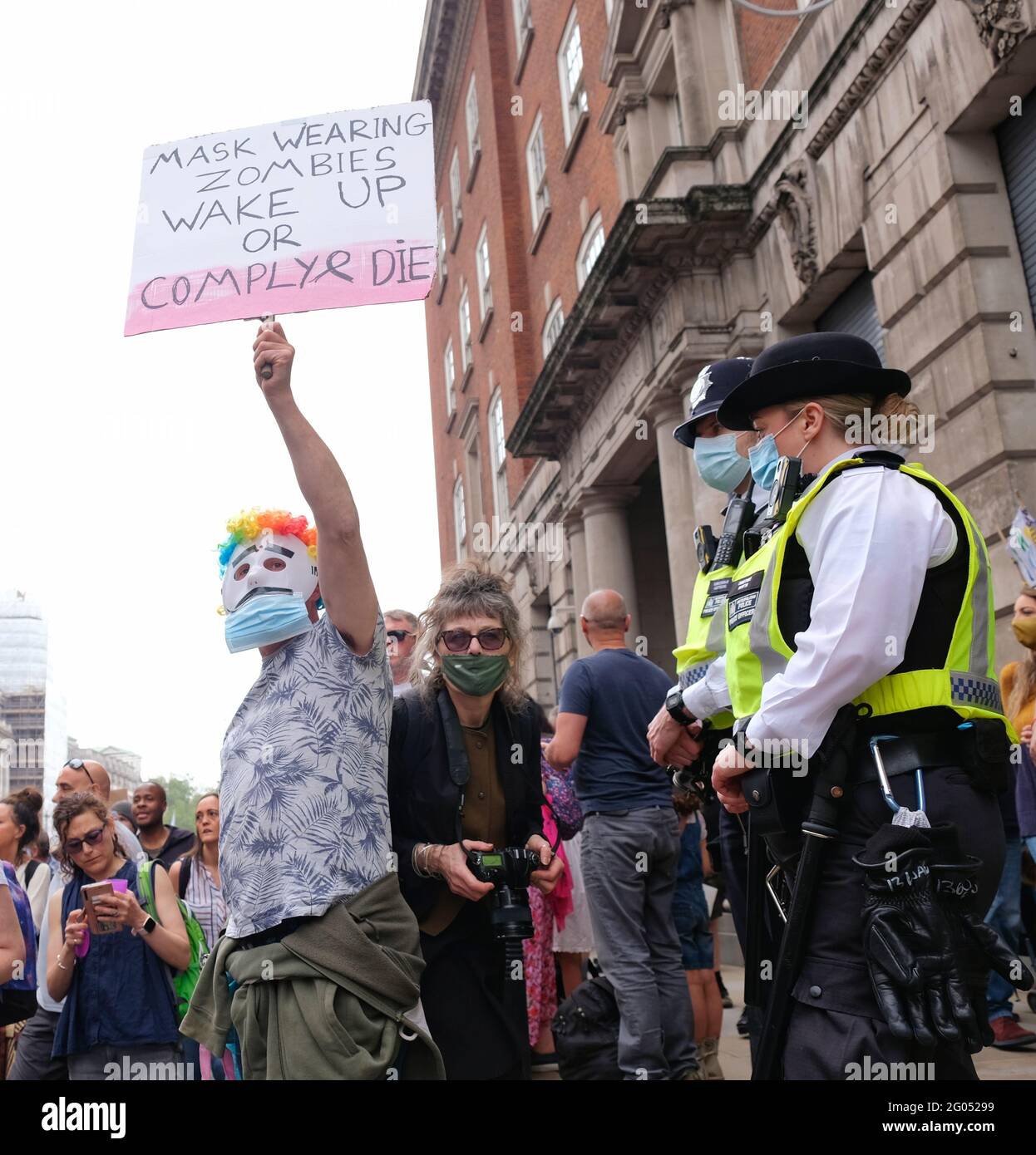 London, Großbritannien. 29/05/21. Ein Protestler steht vor maskierten Polizeibeamten und einem Fotografen, der ein Plakat hochhält, auf dem die Maske angeprangert wird. Stockfoto