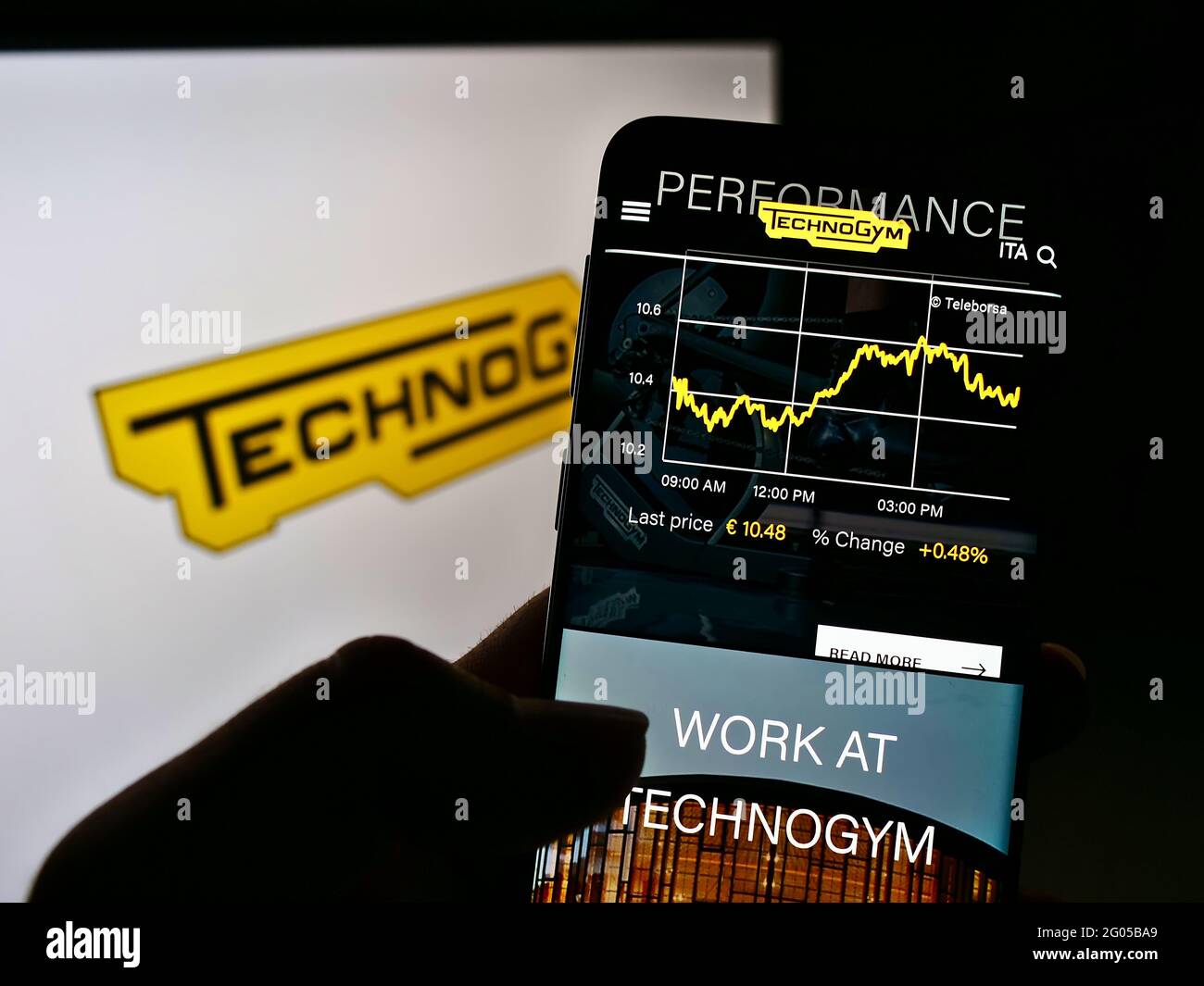 Person mit Mobiltelefon und Webseite des italienischen Fitnessgerätunternehmens Technogym S.p.A. auf dem Bildschirm mit Logo. Konzentrieren Sie sich auf die Mitte des Telefondisplays. Stockfoto