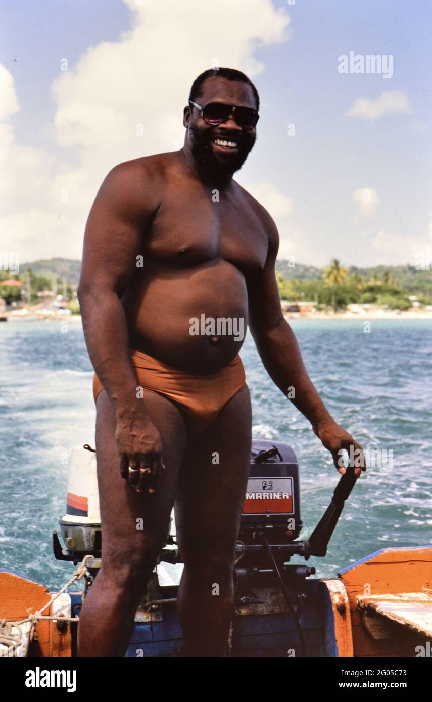 1990er Trinidad und Tobago - Einheimischer in knappen Badeanzug am Steuer des Bootes, Schnorchelausflug in Tobago Ca. 1995 Stockfoto